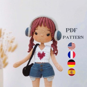 May include: Crochet doll pattern PDF in English, French, German, and Spanish. The doll is wearing a white shirt with a red heart, denim shorts, colorful socks, and black shoes. The doll has brown hair, a pink headband, and headphones.