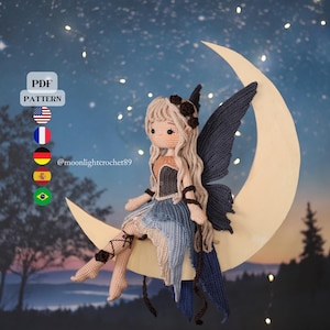 Puede incluir: Una muñeca de hadas de ganchillo con pelo largo rubio, alas azul oscuro y un vestido azul y beige está sentada en una luna creciente. La muñeca tiene un tocado floral y está colocada sobre un fondo de noche estrellada. La imagen incluye el texto "PDF PATTERN".