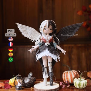 May include: A crochet doll featuring split white and black hair, one white wing, and one black wing. The doll wears a layered white and dark gray outfit with matching boots. Text on the image reads PDF PATTERN with flags and @moonlighterochet89.