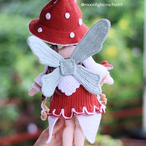 May include: A handmade crochet doll with a red mushroom cap with white spots, a red dress, and light blue wings. The doll has a whimsical fairy design. The text "@moonlightcrochet89" is visible on the image.