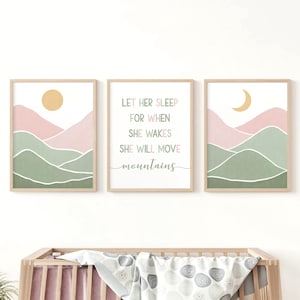 Pode incluir: Três impressões de arte emolduradas com tema de natureza. As impressões apresentam uma paisagem de montanhas, sol e lua em tons de rosa, verde e amarelo. A impressão central tem o texto "LET HER SLEEP FOR WHEN SHE WAKES SHE WILL MOVE mountains".