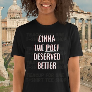 May include: Black t-shirt with white text that reads "Cinna the Poet Deserved Better". The text is repeated in a smaller font size around the main text.