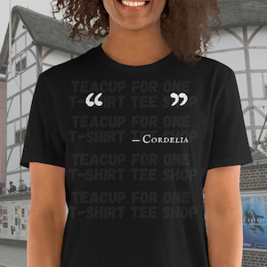 Puede incluir: Camiseta negra con texto blanco que dice "Teacup for One T-Shirt Tee Shop" repetido cuatro veces. El texto está entre comillas y la cuarta repetición incluye el nombre "Cordelia".