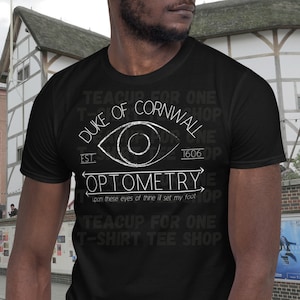 May include: Black t-shirt with a white graphic design that says "Teacup for One T-Shirt Tee Shop Duke of Cornwall Est. 1606 Optometry upon these eyes of thine I'll set my foot Teacup for One T-Shirt Tee Shop".