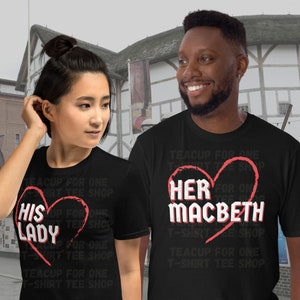 Puede incluir: Dos camisetas negras con un gráfico de corazón rojo y texto que dice "His Lady" y "Her Macbeth". El texto se repite en una fuente más pequeña alrededor del gráfico del corazón. Las camisetas se muestran en dos personas de pie frente a un edificio.
