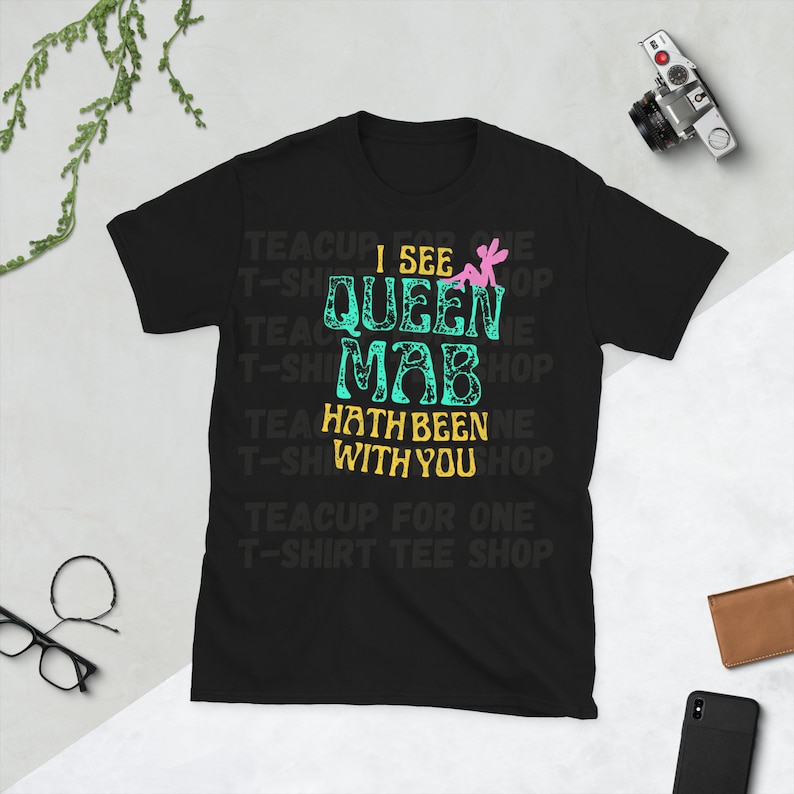 May include: Black t-shirt with a teal and pink graphic that says "I see Queen Mab hath been with you". The graphic is surrounded by the text "Teacup for one T-shirt Tee Shop".
