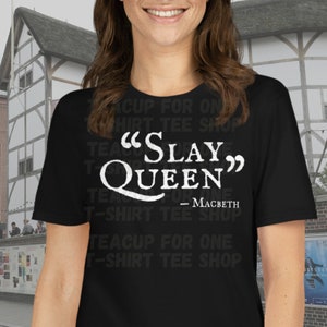 May include: Black t-shirt with white text that reads "SLAY QUEEN" - MACBETH. The text is repeated in a smaller font around the main text.