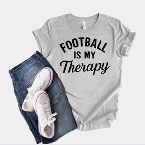 フットボールは私のセラピーTシャツ。フットボール愛好家、試合観戦愛好家、スポーツやアウトドア趣味のファンのための面白いスポーツファンTシャツ。