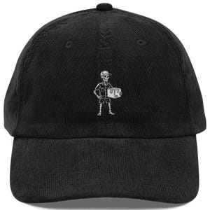 Può includere: Un cappellino da baseball in velluto a coste nero con un ricamo bianco raffigurante uno scheletro che indossa un berretto e un'uniforme mentre tiene in mano una scatola di cartone. Il cappello ha una corona strutturata e una visiera curva.