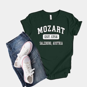 May include: A dark green t-shirt with white text that reads "Mozart Est. 1756 Salzburg, Austria".
