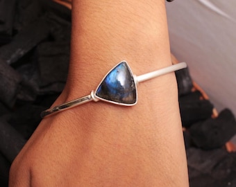 May include: A silver bangle bracelet with a triangular blue labradorite gemstone.