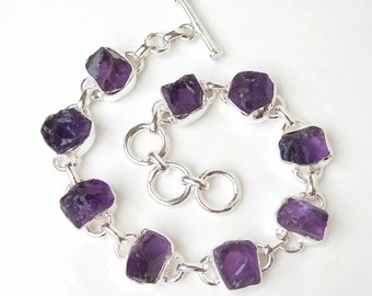 May include: A silver chain bracelet with eight faceted amethyst gemstones. The bracelet has a toggle clasp.