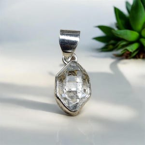 Peut inclure: Un pendentif en cristal clair et facetté avec une bélière argentée. Le cristal a une forme géométrique et est serti dans une lunette argentée. Le pendentif est conçu pour être porté comme bijou.