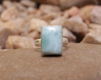 May include: A silver ring with a light blue rectangular gemstone. The gemstone has a cloudy, marbled appearance.