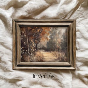 May include: A framed landscape painting depicting a path through a forest with trees and tall grass. The artwork features warm tones of brown, orange, and green. The frame is a light brown color with a textured finish. The text "InVeriitas" is at the bottom.