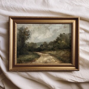 May include: A framed oil painting depicting a landscape scene with a winding dirt road leading through a forest. The painting has a muted color palette with shades of green, brown, and gray.