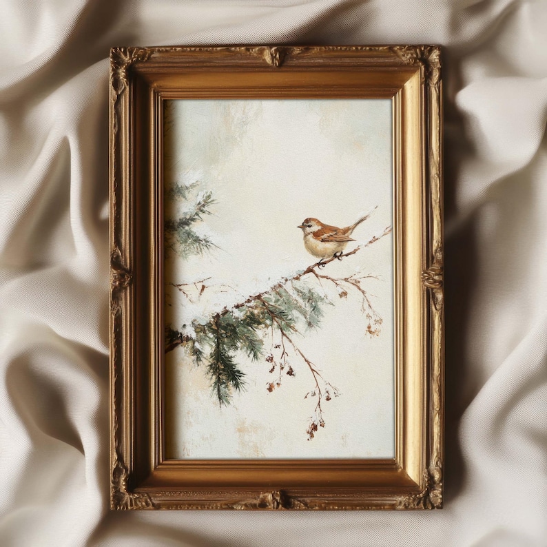 K&ouml;nnte beinhalten: Ein gerahmtes Gem&auml;lde eines kleinen braunen Vogels, der auf einem Zweig eines schneebedeckten Nadelbaums sitzt. Das Gem&auml;lde ist vor einem hellen Hintergrund platziert und in einem goldenen Rahmen gefasst.