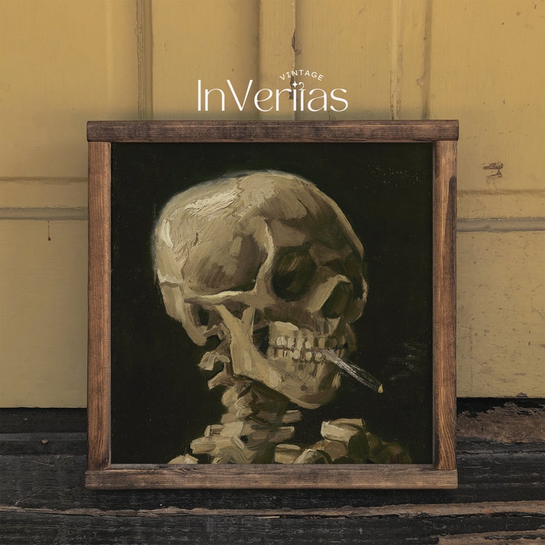 May include: A framed painting of a human skull with a cigarette in its mouth. The skull is painted in a realistic style with a dark background. The frame is brown wood.