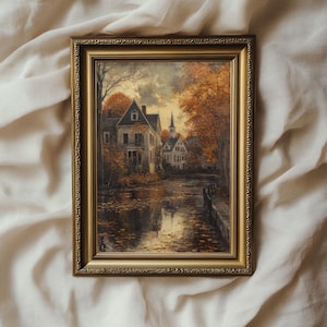 May include: A framed painting depicting a quaint village scene with a river running through it. The houses are painted in muted tones and the trees are a vibrant autumnal orange and yellow. The painting is set against a backdrop of a cloudy sky.
