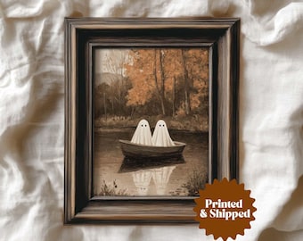 May include: A framed sepia print depicting two ghost figures in a boat on a lake, with autumnal trees in the background. The artwork has a vintage feel, set in a dark brown frame. The print is labelled "Printed & Shipped".