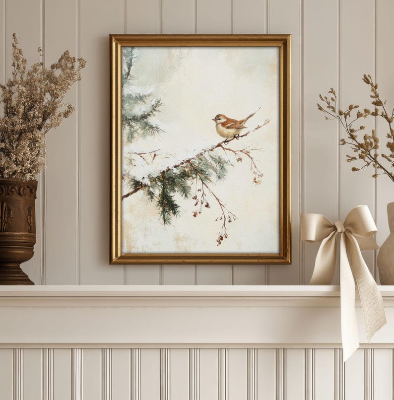 K&ouml;nnte beinhalten: Ein gerahmtes Aquarellbild eines kleinen braunen Vogels, der auf einem schneebedeckten Zweig einer Kiefer sitzt. Der Hintergrund ist in einem sanften, ged&auml;mpften Beige gehalten.