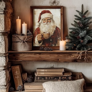 May include: A framed painting of Santa Claus holding a mug of hot chocolate, with candles and a small pine tree on a wooden shelf.