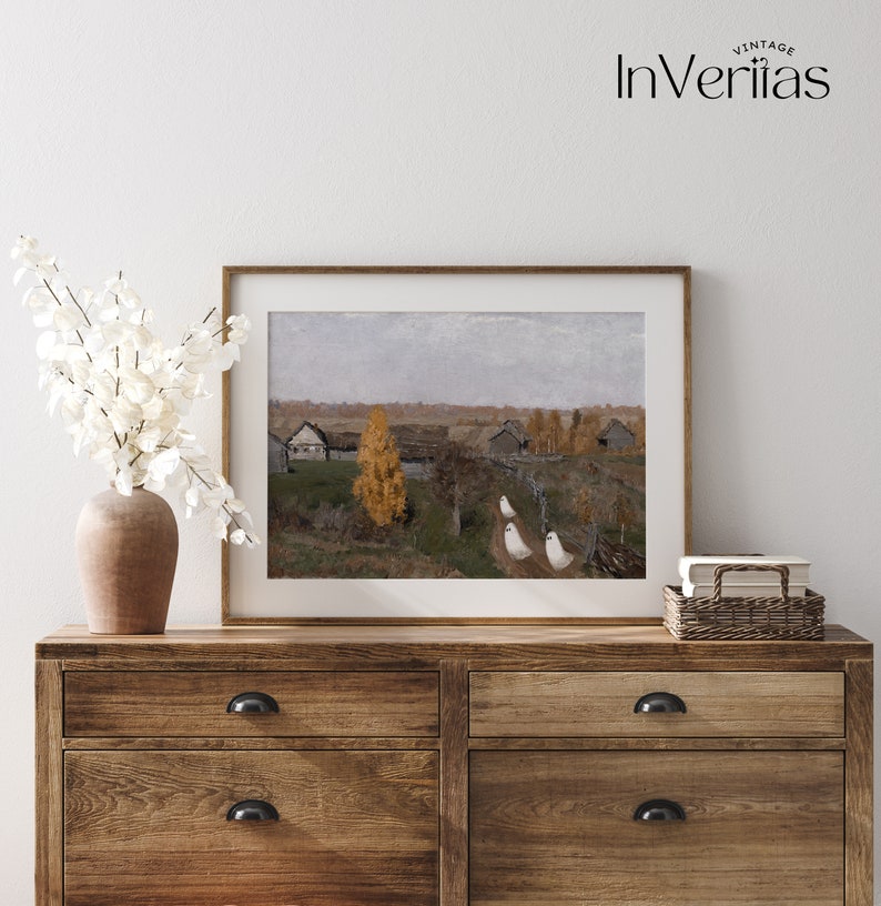 May include: A framed painting of a rural landscape with a small village in the distance. The painting is set against a cloudy sky and features a few trees in the foreground. The painting is displayed on a wooden dresser with a vase of white flowers.