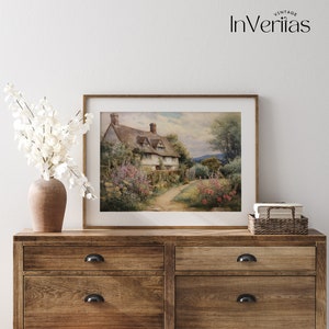 May include: A framed watercolor painting of a cottage with a thatched roof, surrounded by a lush garden with flowers and a winding path. The cottage is set against a backdrop of rolling hills and a blue sky.