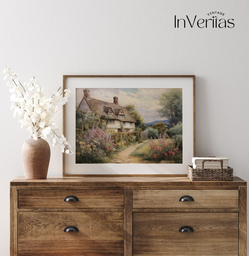 May include: A framed watercolor painting of a cottage with a thatched roof, surrounded by a lush garden with flowers and a winding path. The cottage is set against a backdrop of rolling hills and a blue sky.