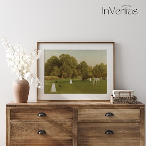 May include: A framed print featuring a pastoral scene with white ghost figures in a green field with horses and trees. The artwork is displayed on a wooden dresser with a vase of white flowers.