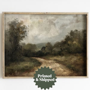 May include: A framed painting of a landscape with a dirt road winding through a forest. The sky is cloudy and the trees are a dark green. The painting is in a simple wooden frame.