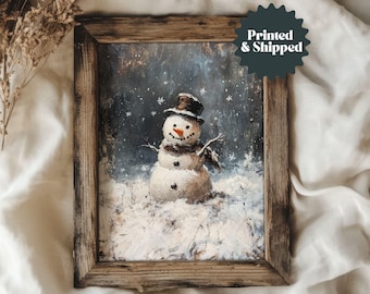 May include: A framed winter-themed painting of a snowman. The snowman has a black top hat, a carrot nose, and a brown scarf. The artwork is set against a snowy backdrop with falling snowflakes. The frame is made of rustic wood.