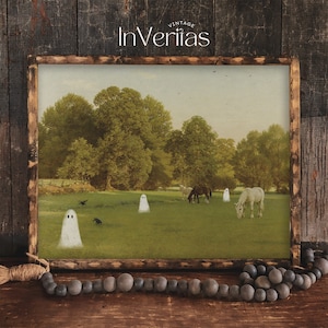 May include: A framed print featuring a pastoral scene with horses grazing in a field, with cartoon ghosts and crows. The print has a rustic wooden frame and the text "Vintage InVeritas" at the top.