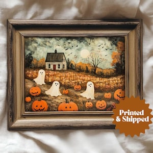 May include: Framed Halloween-themed artwork featuring a quaint white house with a red door, surrounded by pumpkins and friendly ghosts. The autumn landscape includes a full moon, bare trees, and flying bats. The artwork is in a brown wooden frame.