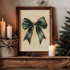 May include: A framed print of a dark green bow on a cream background. The bow is tied with a large knot in the center and the ends of the bow are curled.