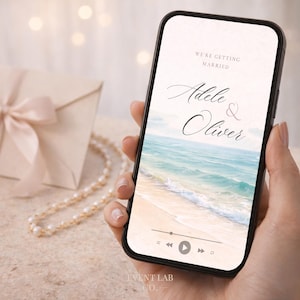 May include: A smartphone screen shows a beach scene with the names "Adele & Oliver" and the text "We're Getting Married." A cream envelope with a bow and a pearl necklace are in the background.