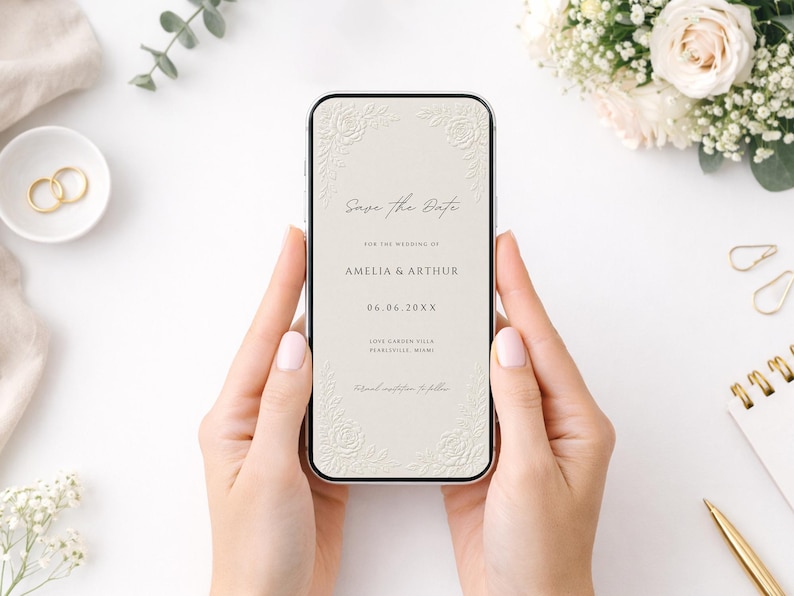Puede incluir: Un tel&eacute;fono inteligente que muestra una invitaci&oacute;n de boda digital Save the Date sobre un fondo crema con esquinas florales en relieve. El texto dice Save the Date, for the wedding of Amelia & Arthur, 06.06.20XX, Love Garden Villa, Pearlesville, Miami.