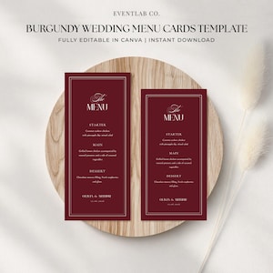 May include: Burgundy wedding menu cards template with text. The cards are rectangular with a white border and a burgundy background. The text includes "The Menu", "Starter", "Main", "Dessert", and names. The cards are on a wooden surface.