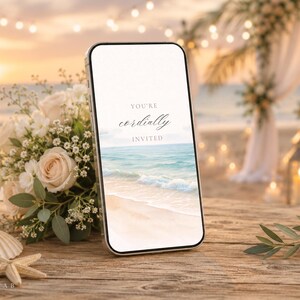 May include: A smartphone displaying a digital wedding invitation with the text "YOU'RE cordially INVITED" over a beach scene. Next to the phone is a bouquet of white roses and baby's breath, a seashell, and a starfish on a wooden surface.