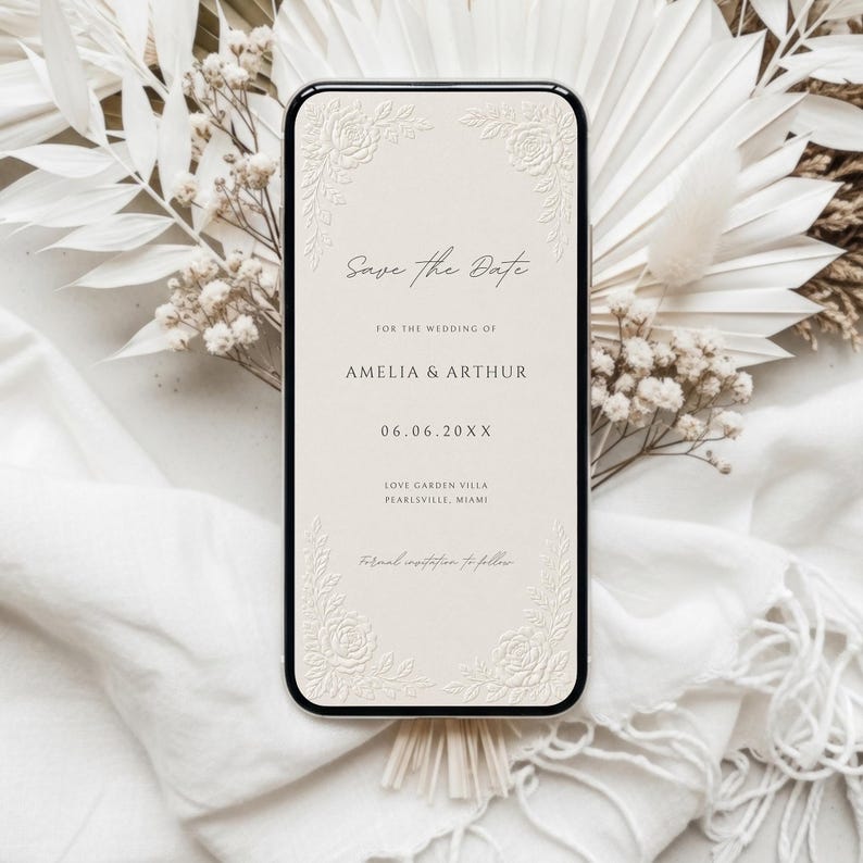 Puede incluir: Una pantalla de smartphone que muestra una tarjeta digital de save the date con fondo crema, esquinas florales en relieve y texto negro que dice Save the Date, Amelia & Arthur, 06.06.20XX, Love Garden Villa, Pearlsville, Miami.