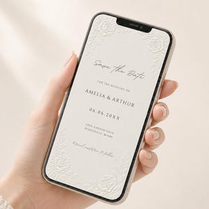 Puede incluir: Un tel&eacute;fono inteligente que muestra una invitaci&oacute;n de boda digital Save the Date sobre un fondo crema con detalles florales blancos en relieve en las esquinas. El texto dice Save the Date for the wedding of Amelia & Arthur, 06.06.20XX, Love Garden Villa, Pearlsville, Miami.