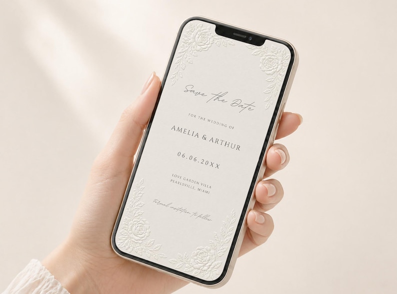 Puede incluir: Un tel&eacute;fono inteligente que muestra una invitaci&oacute;n de boda digital Save the Date sobre un fondo crema con detalles florales blancos en relieve en las esquinas. El texto dice Save the Date for the wedding of Amelia & Arthur, 06.06.20XX, Love Garden Villa, Pearlsville, Miami.