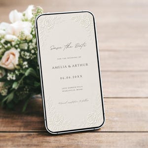 Puede incluir: Un tel&eacute;fono inteligente que muestra un anuncio digital de Save the Date para la boda de Amelia y Arthur el 06.06.20XX, en Love Garden Villa en Pearlsville, Miami. La pantalla tiene un fondo crema con dise&ntilde;os florales en relieve.