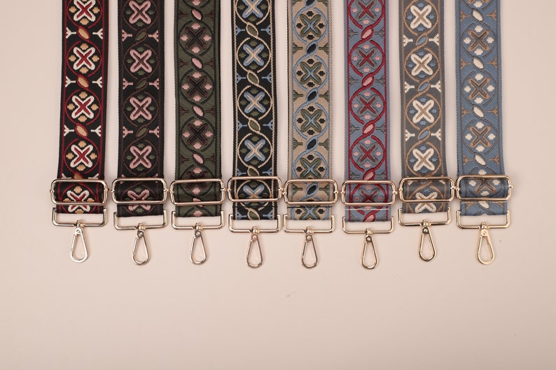 May include: Eight colorful patterned straps with gold metal clasps and swivel hooks. The straps are woven with geometric designs in shades of red, black, green, blue, and beige.
