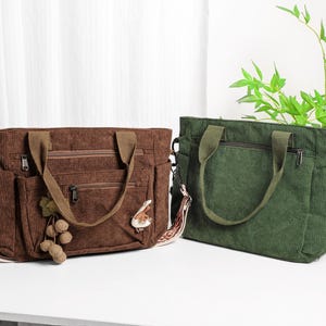 Puede incluir: Dos bolsos tote de pana. Uno es marr&oacute;n con asa marr&oacute;n, un adorno decorativo y una correa estampada. El otro es verde con asa verde. Ambos bolsos tienen m&uacute;ltiples bolsillos y cierre de cremallera.