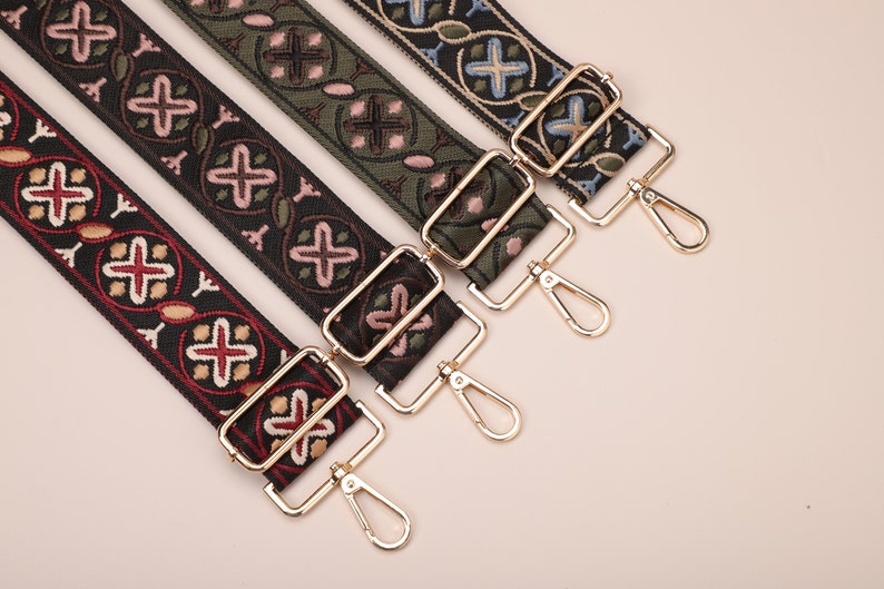 May include: Four different patterned fabric straps with gold metal clasps and swivel hooks. The straps are black, green, blue, and red with intricate floral and geometric designs.