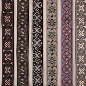May include: Seven different patterned trim ribbons in various colors, including black, green, blue, and beige. The ribbons have a geometric design with repeating patterns.