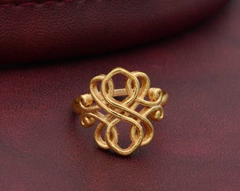 Puede incluir: Anillo de oro con un diseño delicado e intrincado que presenta un patrón repetitivo de espirales y bucles.