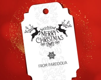 May include: White Christmas gift tag featuring black reindeer silhouettes and the words "MERRY CHRISTMAS". The tag also includes the text "FROM PAREIDOLIA" and a snowflake graphic, set against a red background with gold glitter.