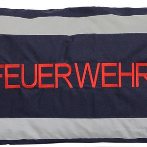 Könnte beinhalten: Ein blaues Kissen mit weißen reflektierenden Streifen und dem in Rot gestickten Wort "FEUERWEHR".